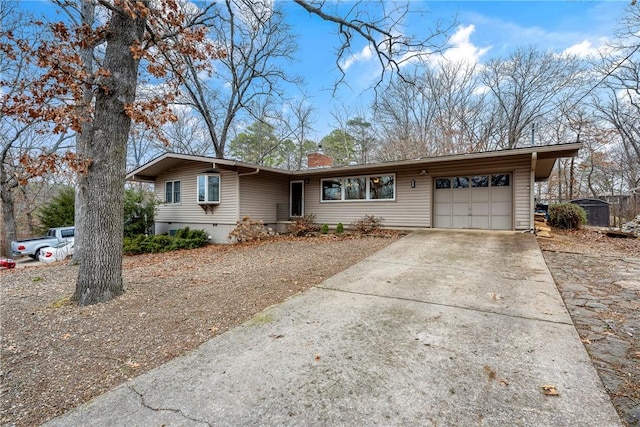 ranch-style home with crawl space, an attached garage, a chimney, and concrete driveway