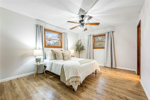 bedroom with a ceiling fan, baseboards, and light wood finished floors