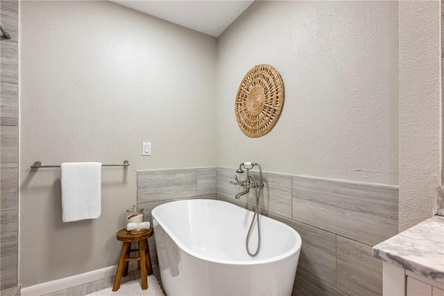 bathroom with vanity, a bath, and tile walls