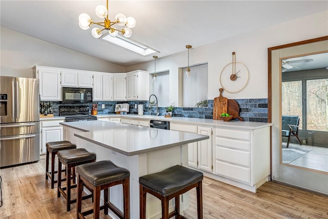 1 Syston Ln, Bella Vista, AR 72714 - kitchen with black appliances, vaulted ceiling, light wood-style floors, white cabinets, and tasteful backsplash