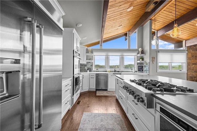 kitchen with dark wood-type flooring, white cabinetry, lofted ceiling with beams, pendant lighting, and stainless steel appliances