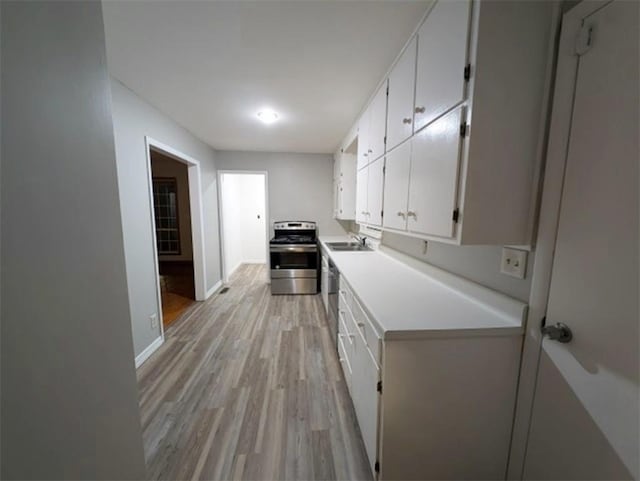 kitchen with white cabinetry, stainless steel appliances, sink, and light hardwood / wood-style floors