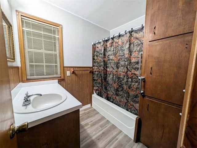 bathroom featuring vanity, hardwood / wood-style floors, shower / bath combination with curtain, and wooden walls