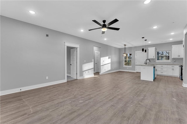 unfurnished living room featuring baseboards, ceiling fan, recessed lighting, light wood-style floors, and a sink