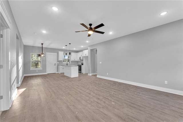 unfurnished living room with baseboards, recessed lighting, light wood-type flooring, and ceiling fan