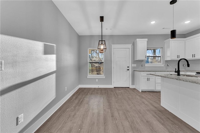 interior space featuring recessed lighting, wood finished floors, baseboards, and a sink