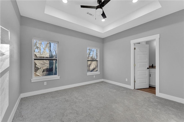 unfurnished bedroom with visible vents, baseboards, a tray ceiling, and carpet floors