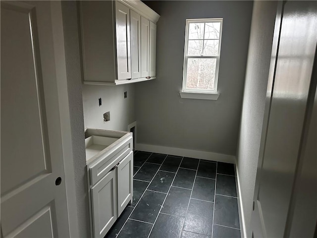 washroom with sink, dark tile patterned flooring, cabinets, washer hookup, and hookup for an electric dryer