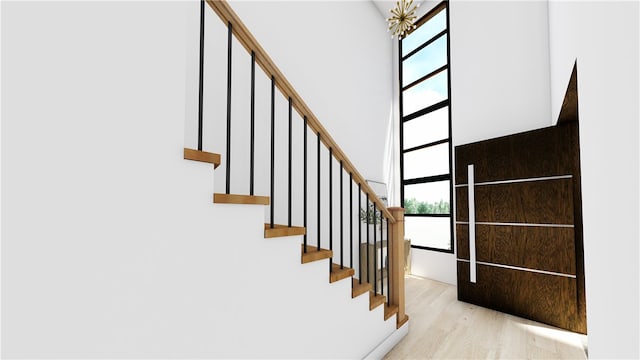 staircase with a towering ceiling and wood-type flooring