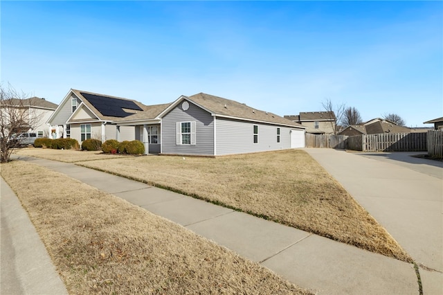 single story home with a front yard and solar panels