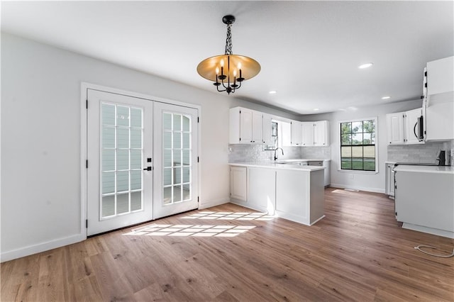 kitchen with sink, hanging light fixtures, light hardwood / wood-style floors, white cabinets, and french doors