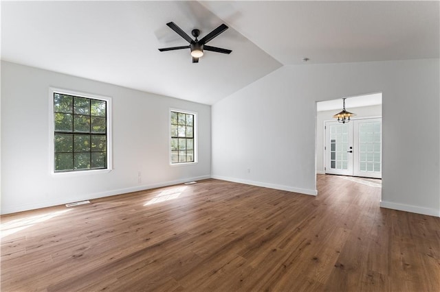 spare room with lofted ceiling, ceiling fan with notable chandelier, wood-type flooring, and french doors