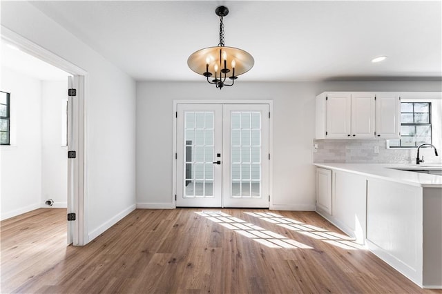 entryway with sink, french doors, a chandelier, and light wood-type flooring