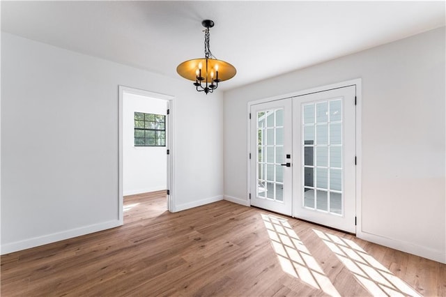 empty room featuring french doors, an inviting chandelier, and hardwood / wood-style floors