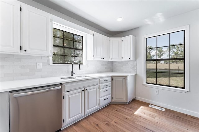 kitchen featuring dishwasher, sink, white cabinets, backsplash, and light hardwood / wood-style floors