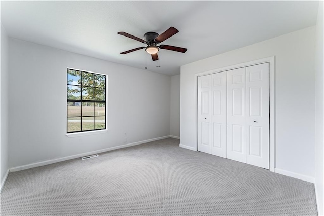 unfurnished bedroom featuring carpet, ceiling fan, and a closet