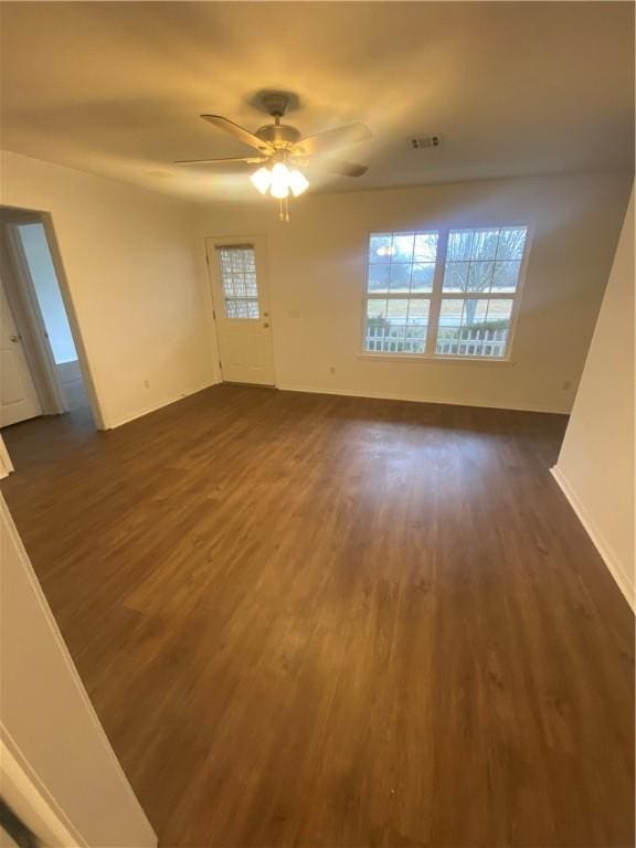 unfurnished living room featuring dark wood-type flooring and ceiling fan