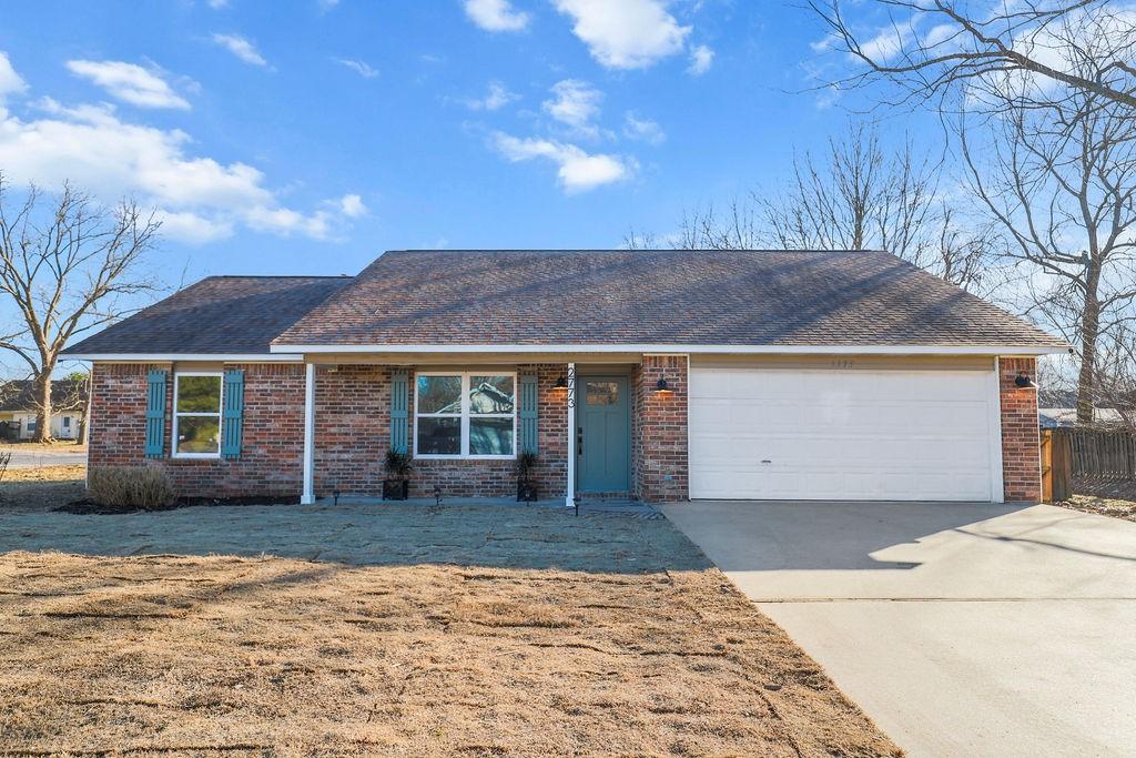 single story home with a garage and a front lawn