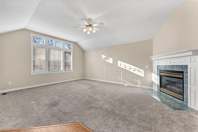 unfurnished living room featuring a tile fireplace, lofted ceiling, carpet, and ceiling fan