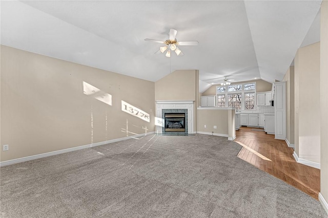 unfurnished living room featuring light carpet, vaulted ceiling, a tile fireplace, and ceiling fan