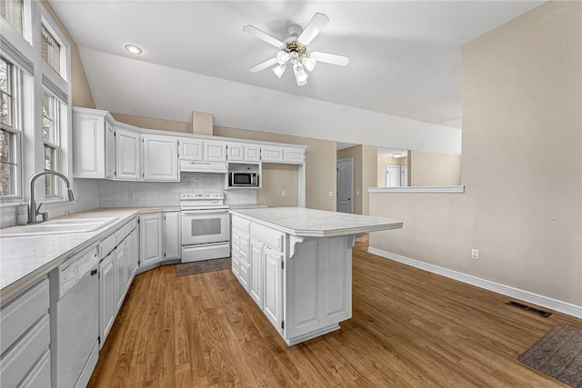 kitchen featuring tasteful backsplash, white cabinetry, sink, white appliances, and light hardwood / wood-style flooring