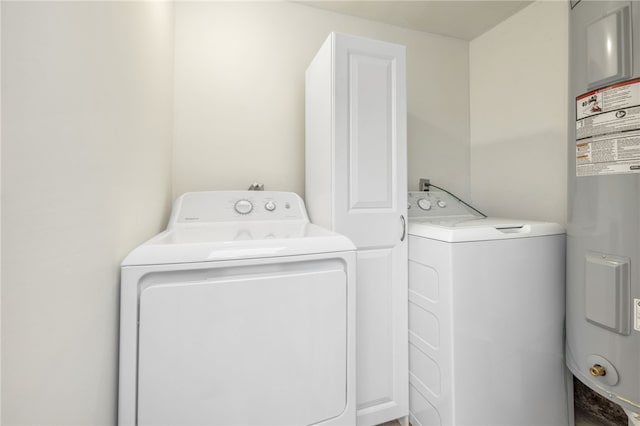 laundry area with water heater, cabinets, and washer and clothes dryer