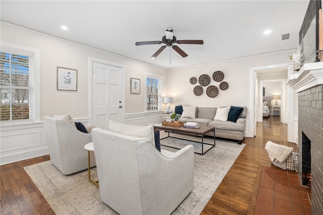 living room featuring ceiling fan, hardwood / wood-style floors, and a brick fireplace