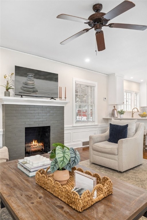 living room featuring wood-type flooring, a fireplace, and sink