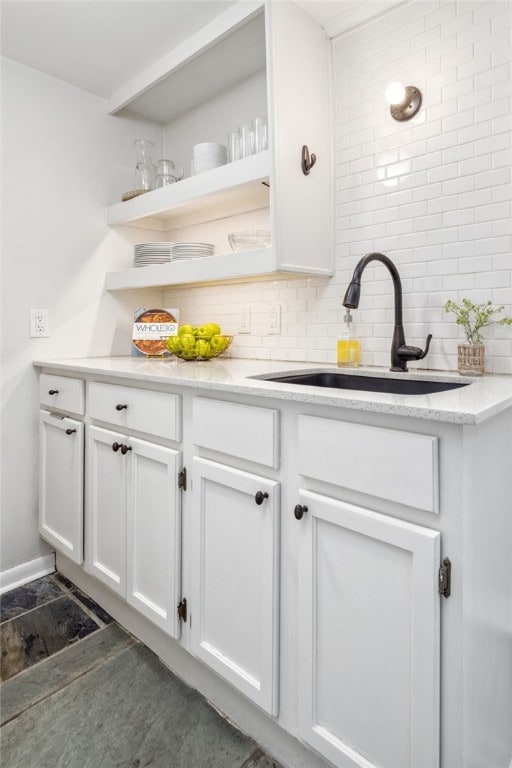 bar featuring white cabinetry, sink, and backsplash