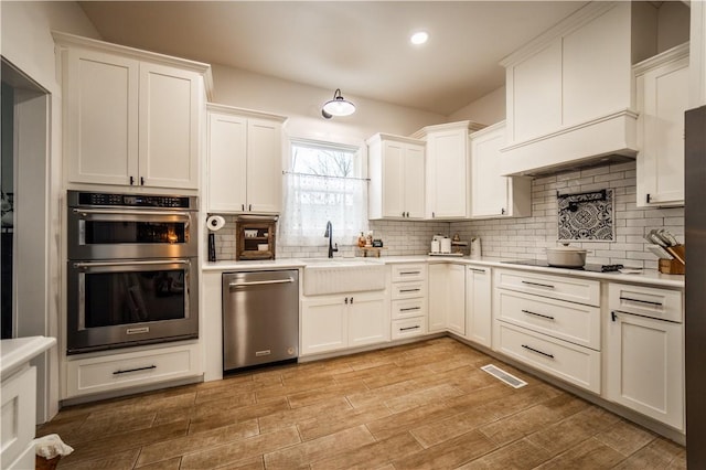 kitchen with stainless steel appliances, sink, decorative backsplash, and white cabinets