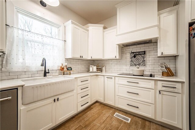 kitchen with white cabinetry, sink, backsplash, stainless steel dishwasher, and black electric cooktop