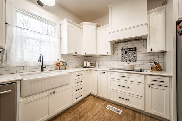 kitchen featuring visible vents, black electric cooktop, a sink, light countertops, and stainless steel dishwasher