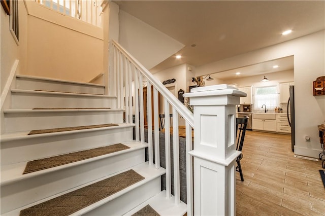 stairway with recessed lighting and wood finished floors