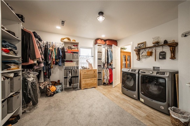 washroom with washing machine and clothes dryer and light wood-type flooring