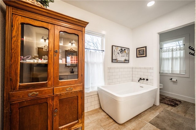 bathroom with toilet, a garden tub, vanity, and recessed lighting