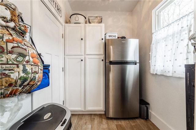 kitchen featuring baseboards, light wood-style floors, white cabinetry, and freestanding refrigerator