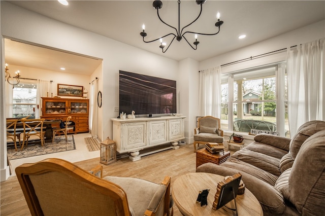 living room with a healthy amount of sunlight, light hardwood / wood-style flooring, and a notable chandelier