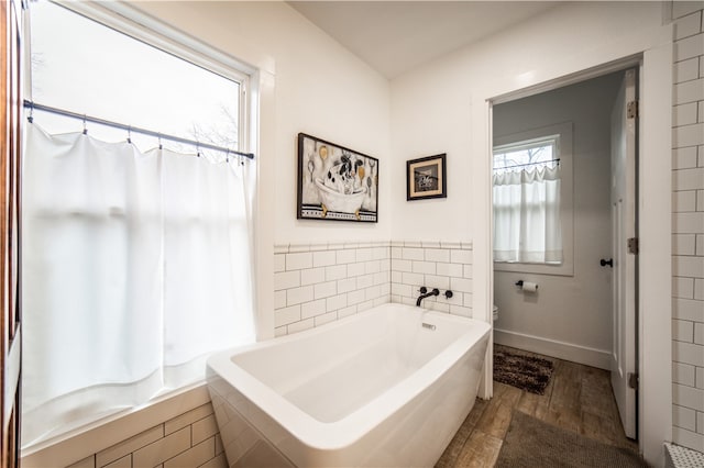 full bathroom with a bathtub, baseboards, toilet, and wood finished floors