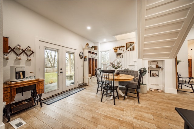 dining room featuring french doors, light wood finished floors, recessed lighting, and stairs