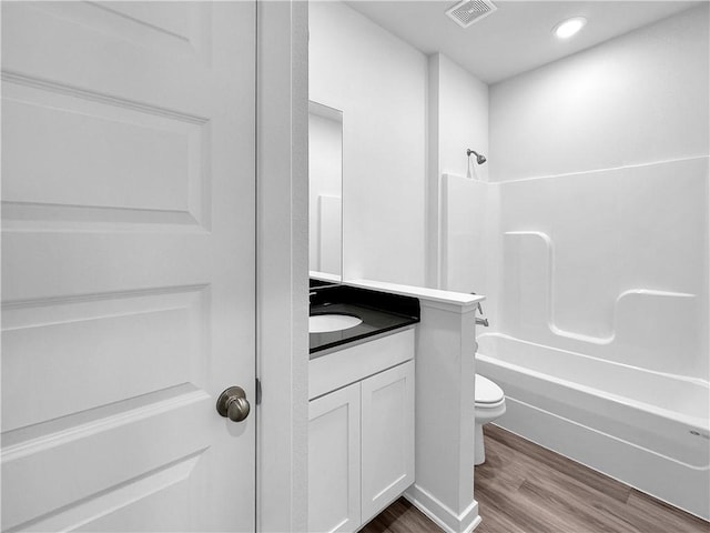 full bathroom featuring hardwood / wood-style flooring, vanity, toilet, and shower / washtub combination