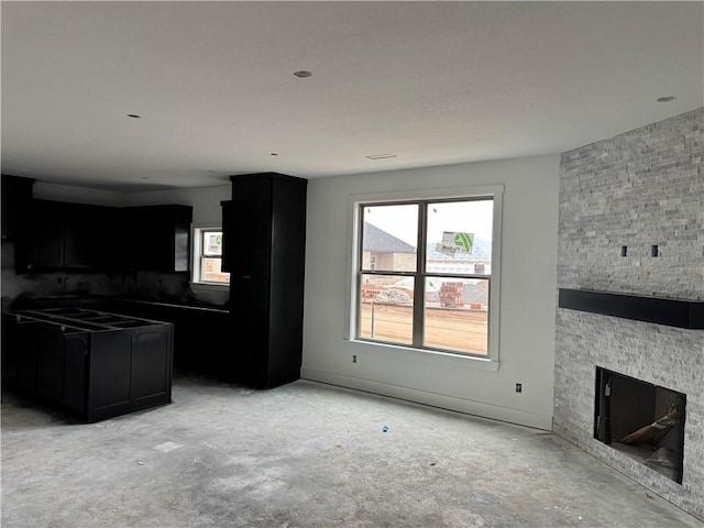 unfurnished living room with a fireplace, concrete floors, and a healthy amount of sunlight