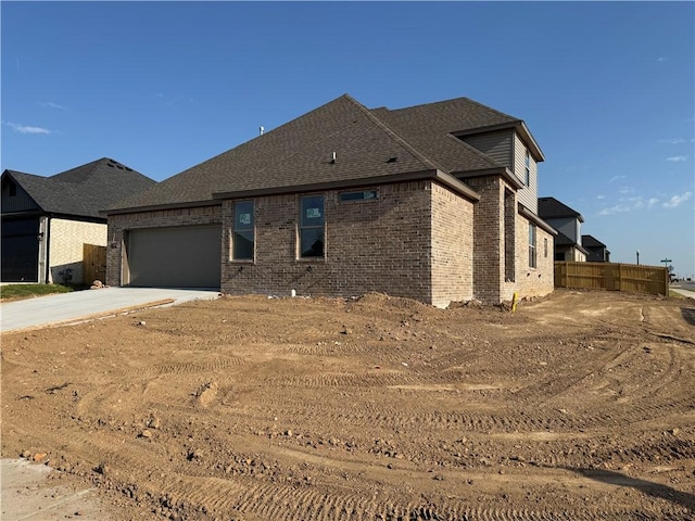exterior space featuring brick siding, fence, driveway, and a garage