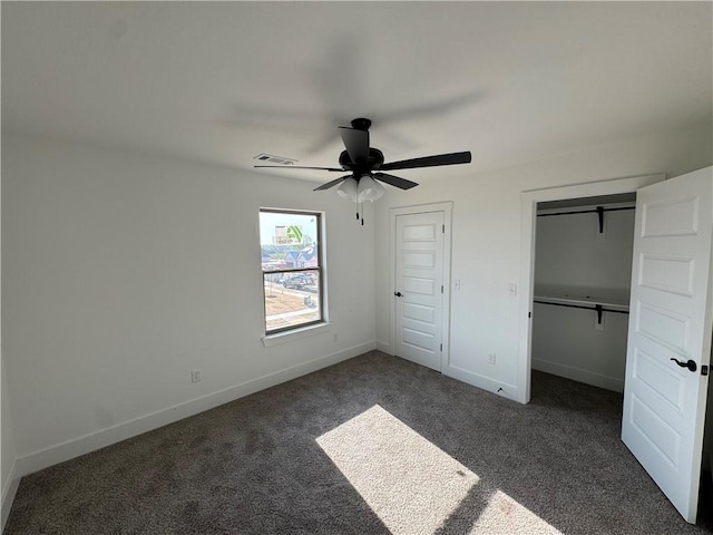 unfurnished bedroom with dark carpet, visible vents, baseboards, two closets, and ceiling fan