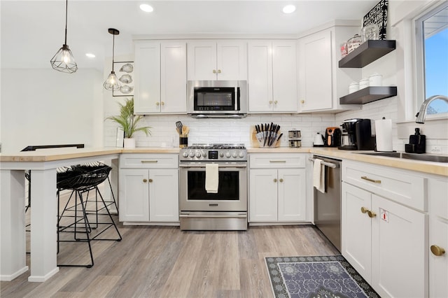 kitchen featuring sink, decorative light fixtures, white cabinets, and appliances with stainless steel finishes