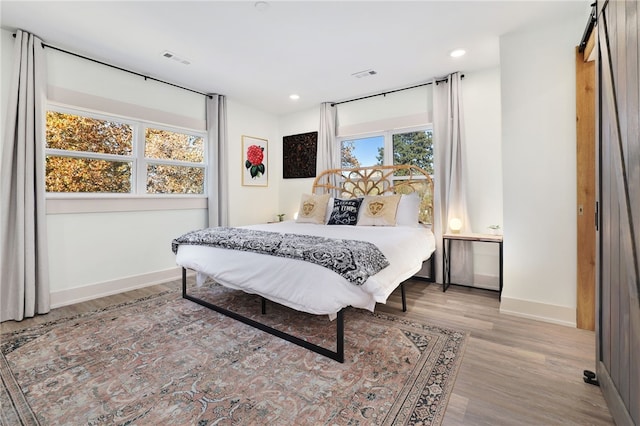 bedroom with a barn door and light wood-type flooring