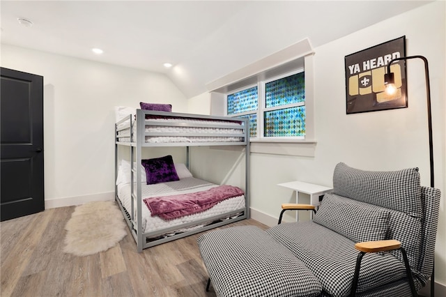 bedroom with vaulted ceiling and light wood-type flooring