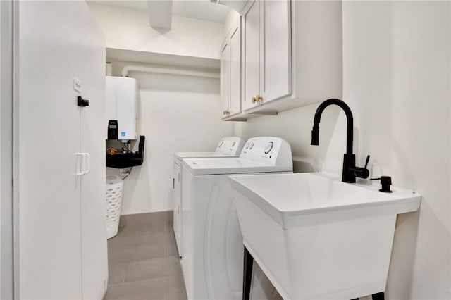 clothes washing area with washing machine and clothes dryer, tankless water heater, sink, cabinets, and light tile patterned floors