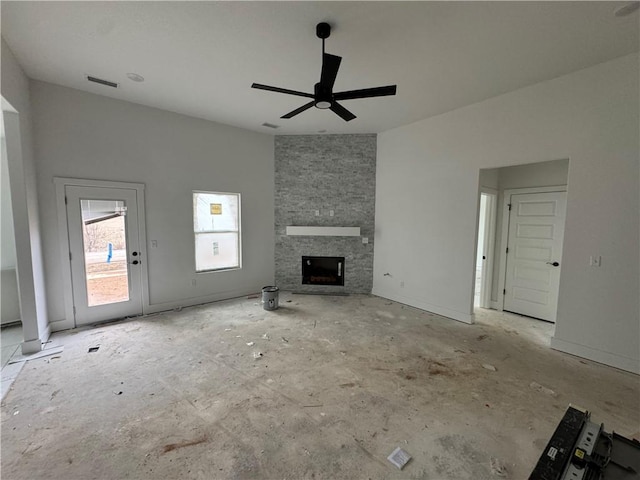 unfurnished living room featuring a stone fireplace and ceiling fan