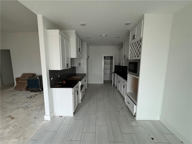 kitchen featuring white cabinetry, backsplash, and built in microwave