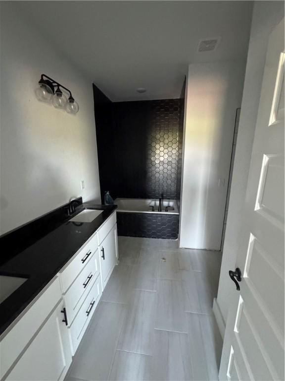 full bathroom featuring tile patterned flooring, double vanity, visible vents, a sink, and a bath
